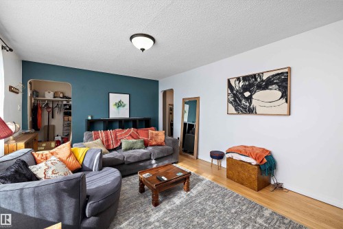 Living area featuring light wood-finish flooring, a contemporary flush mount ceiling light fixture, and a built-in archway opening - 11607 141 Street, Edmonton, AB - Indoor Photo Showing Living Room