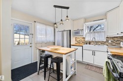 Well-appointed kitchen featuring white cabinetry, stainless steel appliances, butcher block countertops, a tile backsplash, and a farmhouse sink - 
