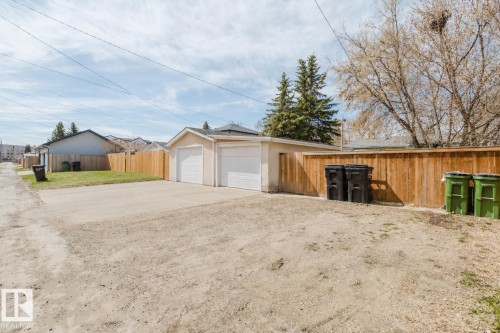 Detached two-car garage with white overhead doors, concrete driveway, and wood privacy fence - 10325 152 Street, Edmonton, AB - Outdoor