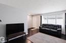 Spacious living area featuring dark wood-finish flooring, light grey walls, and a large window with white blinds - 10325 152 Street, Edmonton, AB  - Indoor Photo Showing Living Room 
