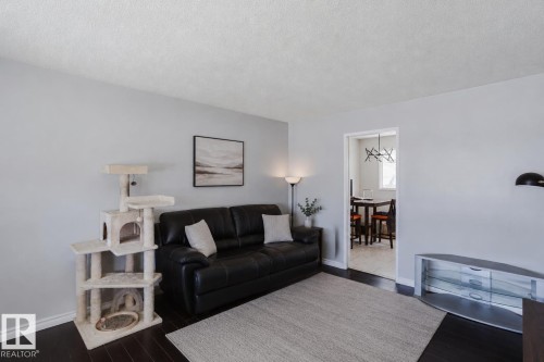 Dark wood-finish flooring complements light gray walls in this living area - 10325 152 Street, Edmonton, AB - Indoor Photo Showing Living Room