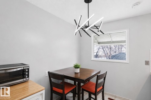 Bright dining area featuring a modern geometric chandelier, a window with exterior views, and neutral wall tones - 10325 152 Street, Edmonton, AB - Indoor Photo Showing Dining Room