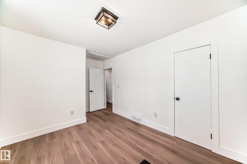 Room featuring wood-finish flooring, white walls, and bright white trim - 8712 89 Avenue, Edmonton, AB 