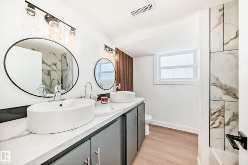 Dual vessel sinks atop a white-veined countertop with gray cabinetry - 8712 89 Avenue, Edmonton, AB 
