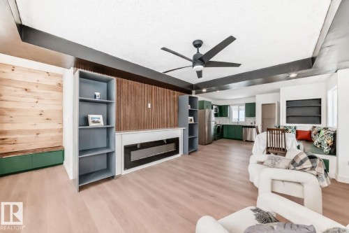 Open-concept living area with wood-finish flooring, a built-in fireplace, and integrated shelving - 8712 89 Avenue, Edmonton, AB 