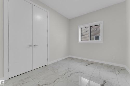 Room featuring large-format porcelain tile flooring with veining, white baseboards, and light gray walls - 12603 44 Street, Edmonton, AB - Indoor Photo Showing Other Room