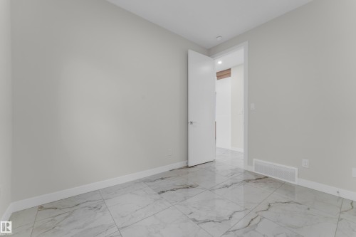 Spacious room featuring large format porcelain tile flooring with dark veining, neutral wall paint, and crisp white baseboards - 12603 44 Street, Edmonton, AB - Indoor Photo Showing Other Room