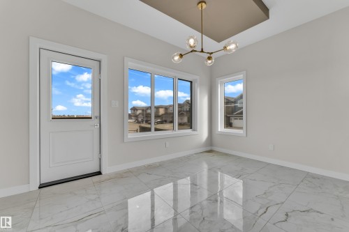 Spacious room featuring large format marble-look tile flooring, white baseboards, and bright white walls - 12603 44 Street, Edmonton, AB - Indoor Photo Showing Other Room