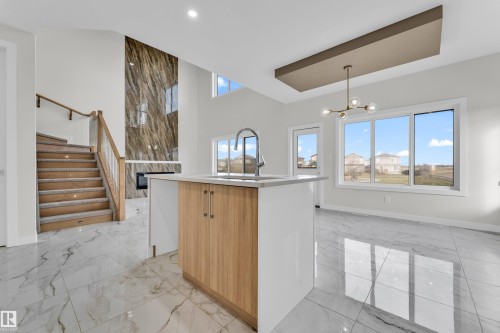 Kitchen island with integrated sink, wood-finish cabinetry, and light-toned countertop - 12603 44 Street, Edmonton, AB - Indoor Photo Showing Other Room