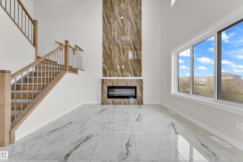 Two-story living area featuring a prominent fireplace with a floor-to-ceiling stone-look surround and an integrated electric firebox - 12603 44 Street, Edmonton, AB - Indoor Photo Showing Other Room With Fireplace