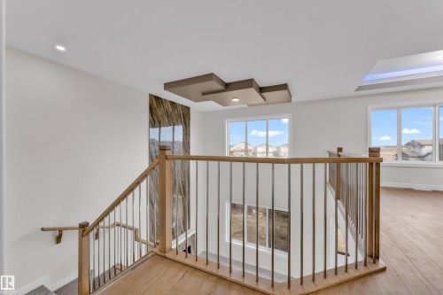 Upper-level landing featuring wood-finish flooring, a modern wood and metal railing, recessed lighting, and a decorative ceiling panel - 12603 44 Street, Edmonton, AB - Indoor Photo Showing Other Room