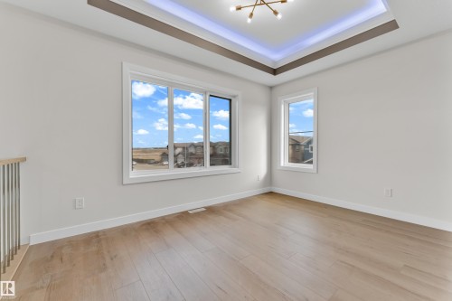 Spacious room featuring wood-finish flooring, white baseboards, and a tray ceiling with integrated lighting - 12603 44 Street, Edmonton, AB - Indoor Photo Showing Other Room
