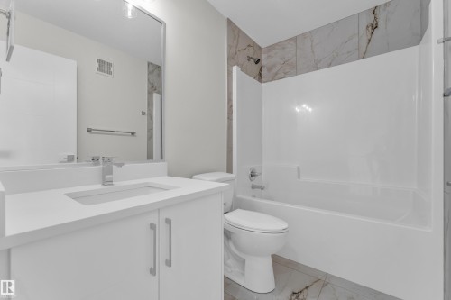 Modern bathroom featuring a white vanity with integrated sink, chrome faucet, and expansive wall mirror - 12603 44 Street, Edmonton, AB - Indoor Photo Showing Bathroom