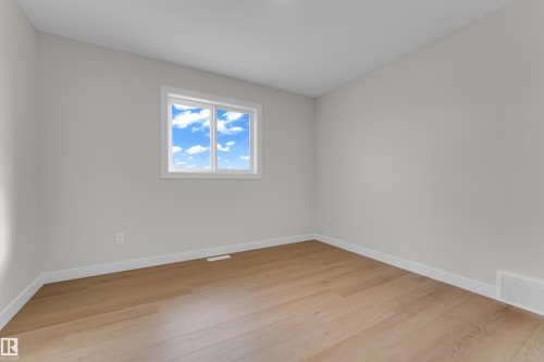Bright room featuring a prominent window, light wood-finish flooring, white baseboards, and neutral wall tones - 12603 44 Street, Edmonton, AB - Indoor Photo Showing Other Room
