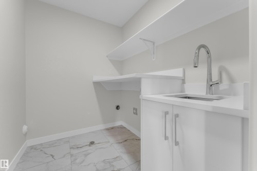 Utility space featuring white cabinetry, a built-in sink with a chrome faucet, white countertops, and a white floating shelf - 12603 44 Street, Edmonton, AB - Indoor With Storage