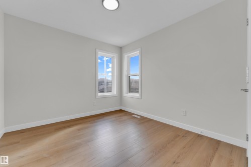 Neutral painted walls featuring wood-finish flooring, white baseboards, and two single-hung windows - 12603 44 Street, Edmonton, AB - Indoor Photo Showing Other Room
