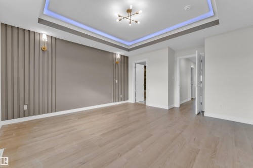 Spacious room featuring light wood-finish flooring and a tray ceiling with accent lighting - 12603 44 Street, Edmonton, AB - Indoor Photo Showing Other Room
