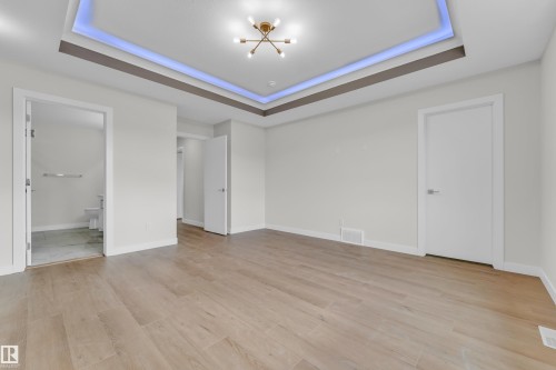 Spacious room with recessed tray ceiling featuring accent lighting and a modern brass light fixture - 12603 44 Street, Edmonton, AB - Indoor Photo Showing Other Room