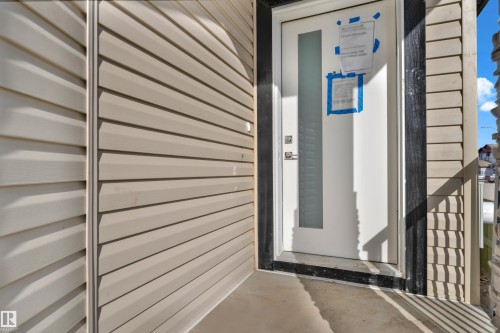 White entry door with a frosted glass panel, contemporary hardware, and dark trim, complemented by light-toned siding - 12603 44 Street, Edmonton, AB - Outdoor With Exterior