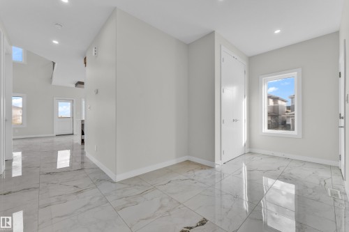 Spacious entryway featuring large format tile flooring, recessed lighting, and a white paneled door - 12603 44 Street, Edmonton, AB - Indoor Photo Showing Other Room