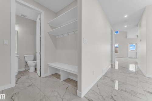 Entryway featuring marble-look tile flooring, built-in bench with shelving and coat hooks, recessed lighting, and a powder room with a vanity and toilet - 12603 44 Street, Edmonton, AB - Indoor
