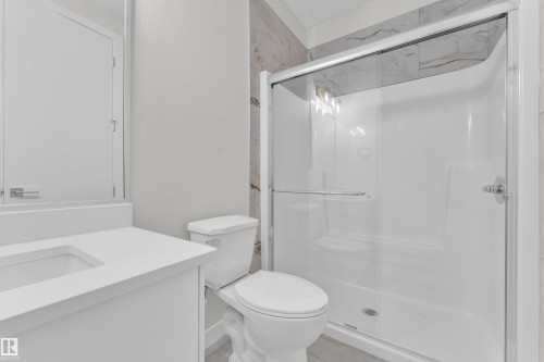 Contemporary bathroom featuring a white vanity with an integrated sink, a white toilet, and a stand-up shower with clear glass sliding doors - 12603 44 Street, Edmonton, AB - Indoor Photo Showing Bathroom