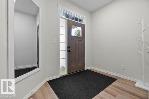 Entryway with wood-finish flooring, a solid panel door with upper glass, and vertical sidelight windows - 3623 6 Street, Edmonton, AB - Indoor Photo Showing Other Room