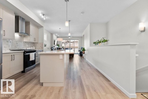 Modern kitchen featuring light cabinetry, stainless steel appliances, a tile backsplash, and an island with pendant lighting - 3623 6 Street, Edmonton, AB - Indoor Photo Showing Kitchen With Upgraded Kitchen