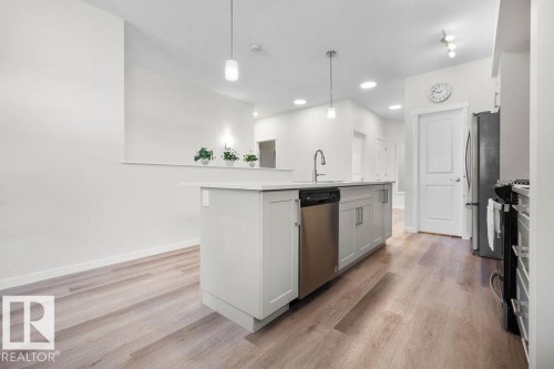 Modern kitchen featuring a light gray island with integrated sink, stainless steel dishwasher, and pendant lighting - 3623 6 Street, Edmonton, AB - Indoor Photo Showing Kitchen With Upgraded Kitchen
