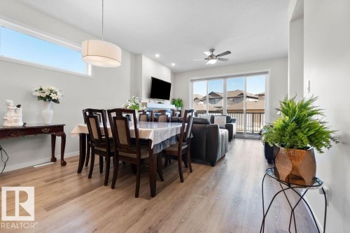 Open-concept living area featuring light wood-finish flooring, a long rectangular dining table, and a contemporary pendant light fixture - 3623 6 Street, Edmonton, AB - Indoor Photo Showing Dining Room