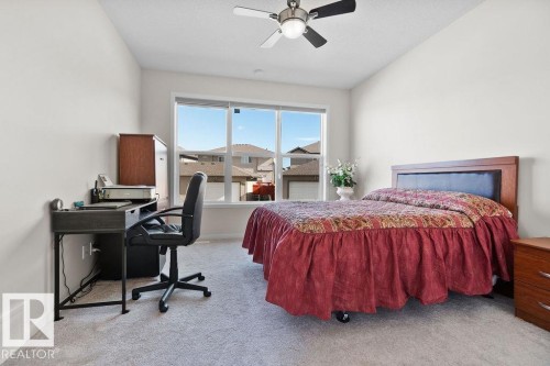 Carpeted room featuring a large window, a ceiling fan with integrated lighting, and neutral wall tones - 3623 6 Street, Edmonton, AB - Indoor Photo Showing Bedroom