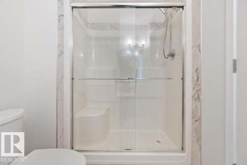Shower enclosure with clear glass sliding doors and a built-in bench - 3623 6 Street, Edmonton, AB - Indoor Photo Showing Bathroom