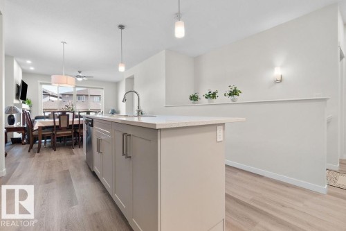 Kitchen island with light-toned cabinetry, stainless steel dishwasher, and a light-colored countertop - 3623 6 Street, Edmonton, AB - Indoor Photo Showing Kitchen With Upgraded Kitchen