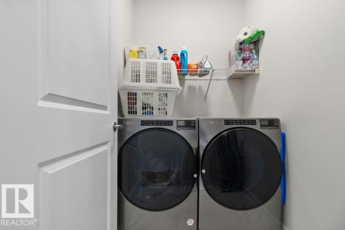 Dedicated laundry area featuring a front-loading washer and dryer, a wall-mounted wire shelf, and a modern interior door with geometric paneling - 3623 6 Street, Edmonton, AB - Indoor Photo Showing Laundry Room