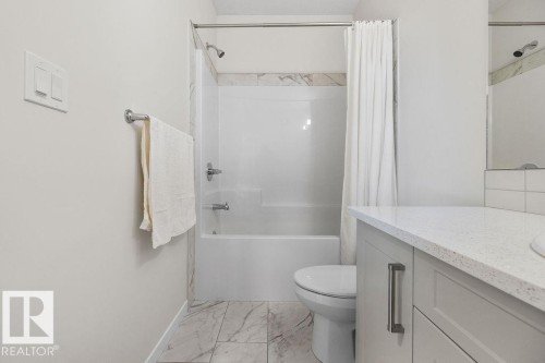 Contemporary bathroom featuring a white tub/shower combination with a marble-effect surround, a white toilet, and marble-effect floor tiles - 3623 6 Street, Edmonton, AB - Indoor Photo Showing Bathroom