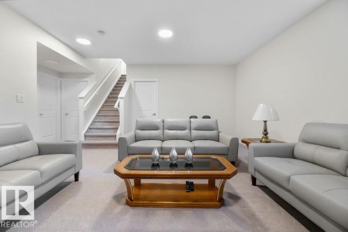 Spacious carpeted living area featuring recessed lighting, a neutral color palette, and a carpeted staircase with white railings - 3623 6 Street, Edmonton, AB - Indoor Photo Showing Living Room