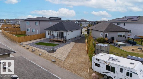 Exterior featuring a rear deck with black railings, a gravel and paver patio, and a fenced yard with artificial turf - 3623 6 Street, Edmonton, AB - Outdoor