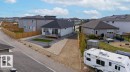 Exterior featuring a rear deck with black railings, a gravel and paver patio, and a fenced yard with artificial turf - 3623 6 Street, Edmonton, AB  - Outdoor 