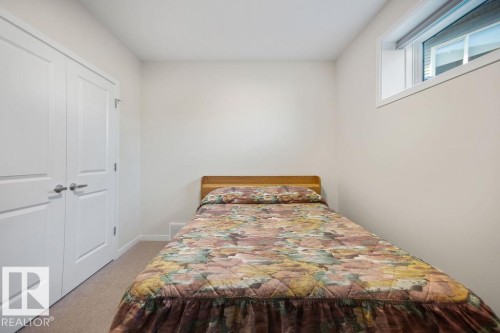 Bedroom featuring light beige carpeting, white walls, a high-set window, and double bi-fold closet doors with brushed nickel hardware - 3623 6 Street, Edmonton, AB - Indoor Photo Showing Bedroom