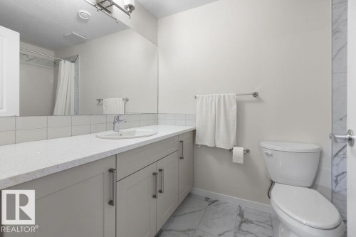 Bathroom vanity featuring a light-toned countertop, undermount sink, and shaker-style cabinetry with brushed nickel hardware - 3623 6 Street, Edmonton, AB - Indoor Photo Showing Bathroom