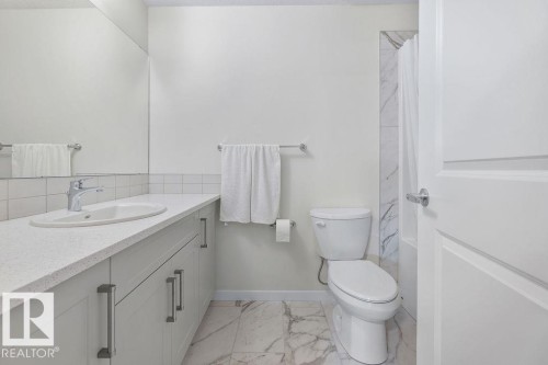 Contemporary bathroom featuring a spacious vanity with an undermount sink, a chrome faucet, light-toned cabinetry with bar pull hardware, and a large mirror - 3623 6 Street, Edmonton, AB - Indoor Photo Showing Bathroom