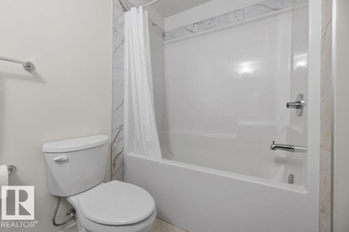 Bathroom featuring a white tub/shower combination, chrome fixtures, and marble-patterned tile accents - 3623 6 Street, Edmonton, AB - Indoor Photo Showing Bathroom