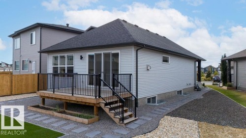 Rear exterior featuring light-colored siding, a dark shingle roof, and a wood deck with black railings - 3623 6 Street, Edmonton, AB - Outdoor With Exterior