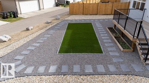 Landscaped backyard featuring an artificial turf centerpiece, surrounded by gravel, and bordered by concrete stepping stones - 3623 6 Street, Edmonton, AB - Outdoor