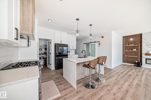 Open-concept kitchen featuring white cabinetry, a central island with bar seating, and recessed lighting - 3247 Chernowski Way, Edmonton, AB - Indoor Photo Showing Kitchen With Upgraded Kitchen