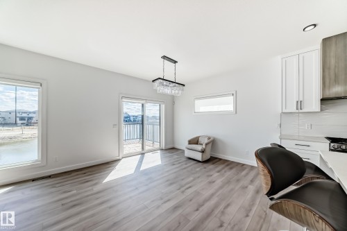 Open-concept living area featuring wood-finish flooring and ample natural light - 3247 Chernowski Way, Edmonton, AB - Indoor