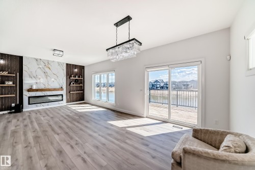 Spacious interior featuring wide plank wood-finish flooring and a contemporary fireplace with a stone-look surround and wood mantle - 3247 Chernowski Way, Edmonton, AB - Indoor