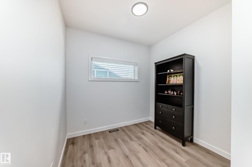 Bright room featuring wood-finish flooring, crisp white walls, and a recessed window with blinds - 3247 Chernowski Way, Edmonton, AB - Indoor