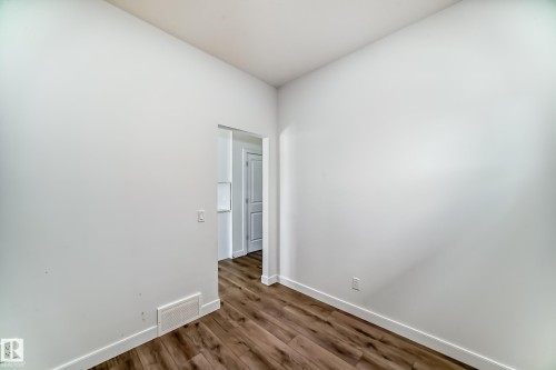 Room featuring wood-finish flooring, white baseboards, and a doorway opening to another interior space - 3247 Chernowski Way, Edmonton, AB - Indoor Photo Showing Other Room