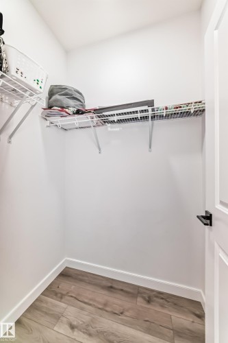 Recessed closet space featuring wood-finish flooring, white baseboards, and built-in wire shelving - 3247 Chernowski Way, Edmonton, AB - Indoor With Storage